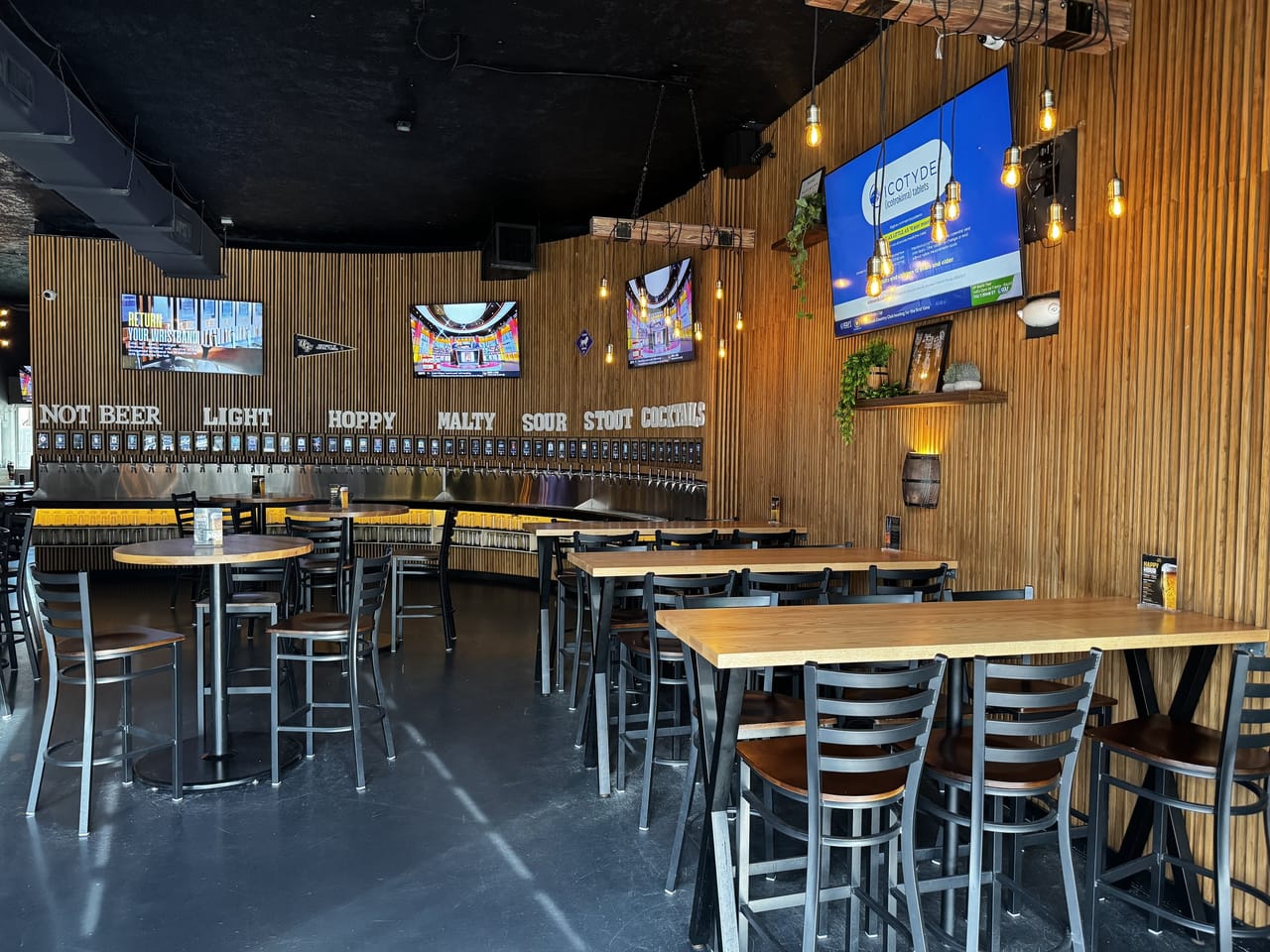 High-top tables facing the self-pour tap wall inside Pour Choice Taphouse in Mills 50 Orlando