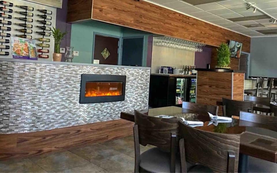 Interior of Pop Thai next door, with dark wood tables and a tiled counter fireplace